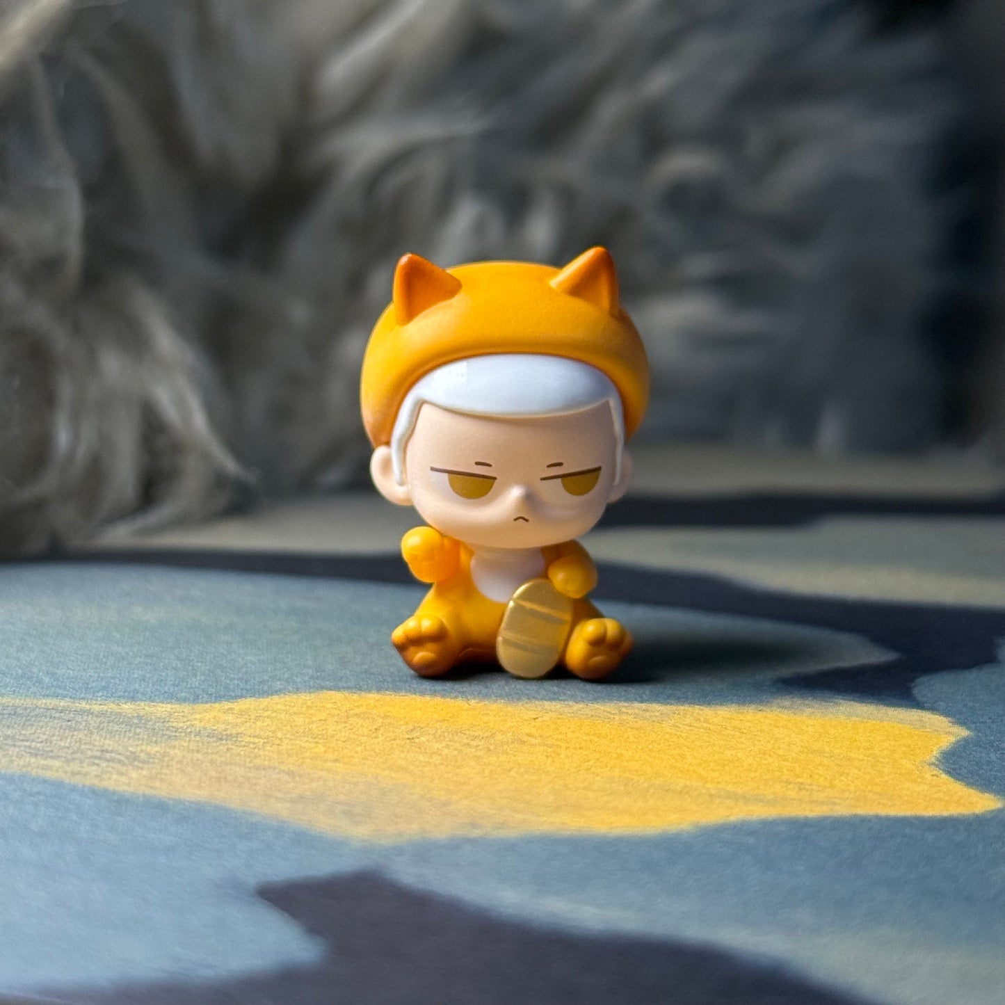 Small figurine with a yellow hat and outfit on a textured surface